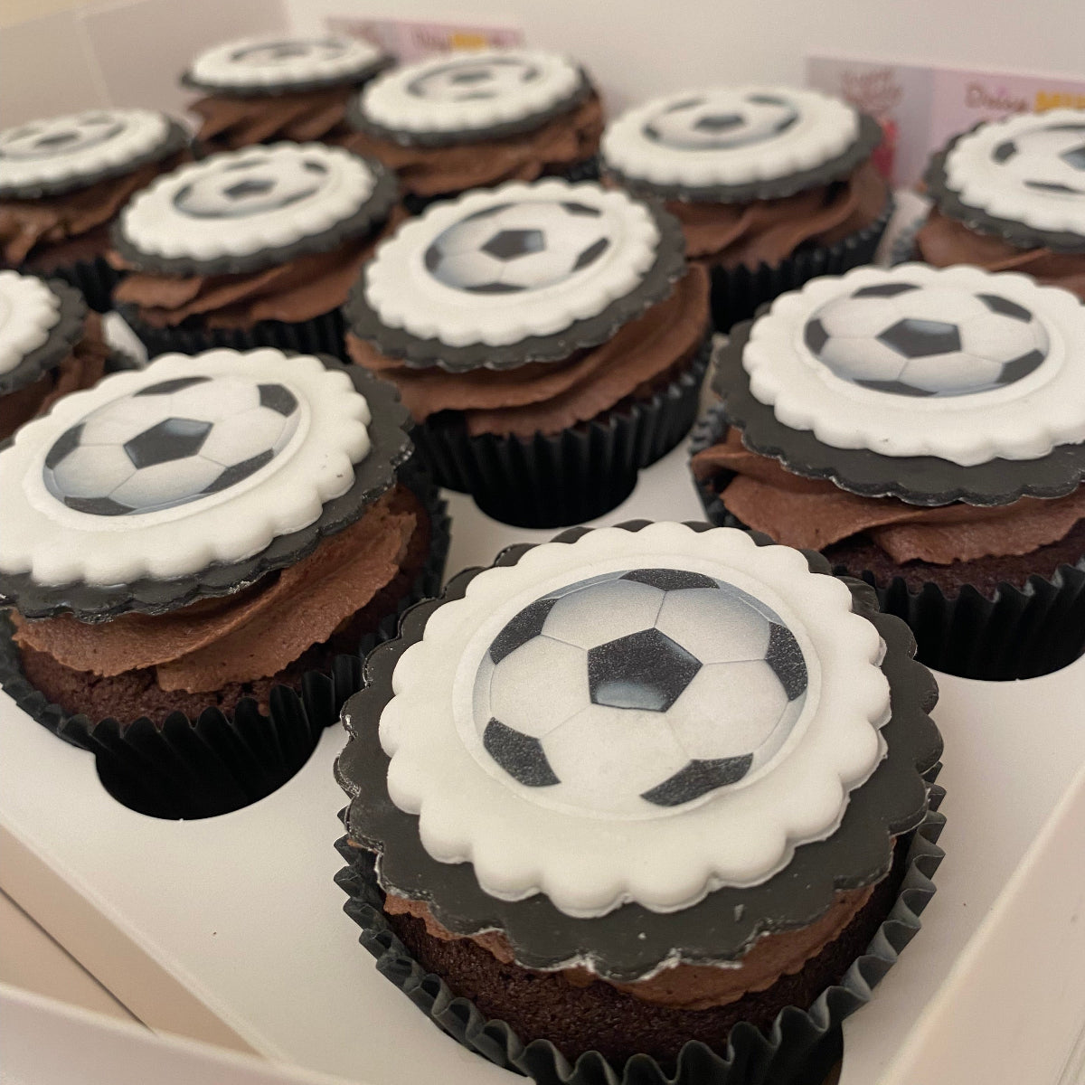 Cupcakes with soccer ball designs on top arranged in a box.