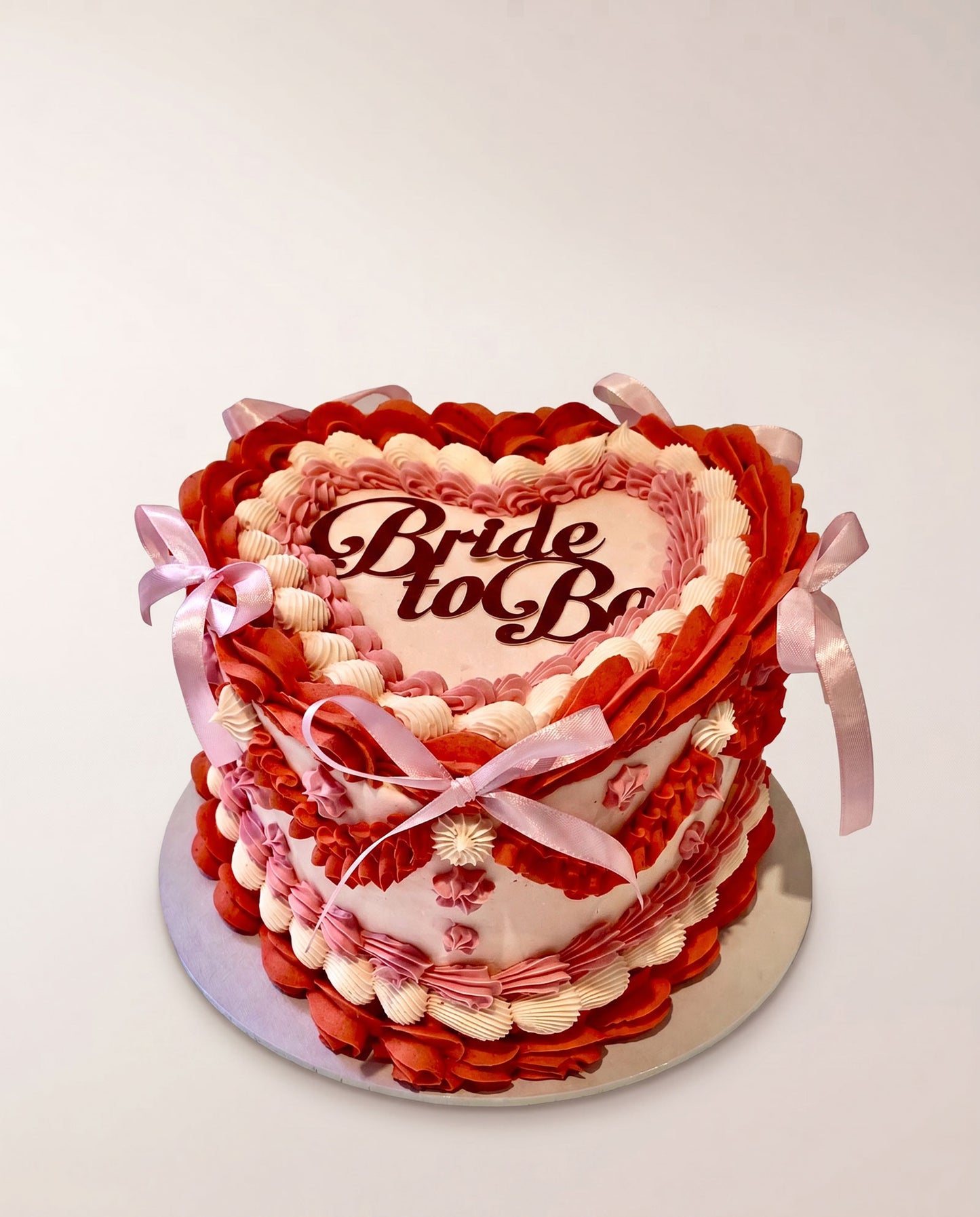 Heart-shaped buttercream cake hand-piped in red, pink and cream with a bride-to-be topper, handmade by Daisy Mud Pie in Brentwood, Essex