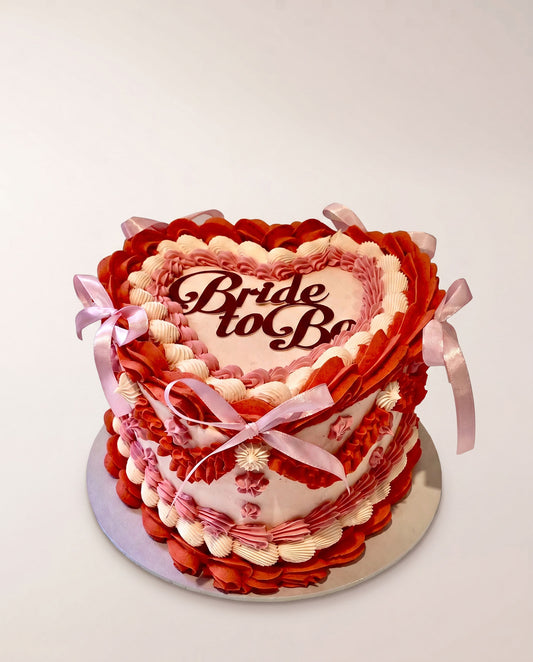Heart-shaped buttercream cake hand-piped in red, pink and cream with a bride-to-be topper, handmade by Daisy Mud Pie in Brentwood, Essex