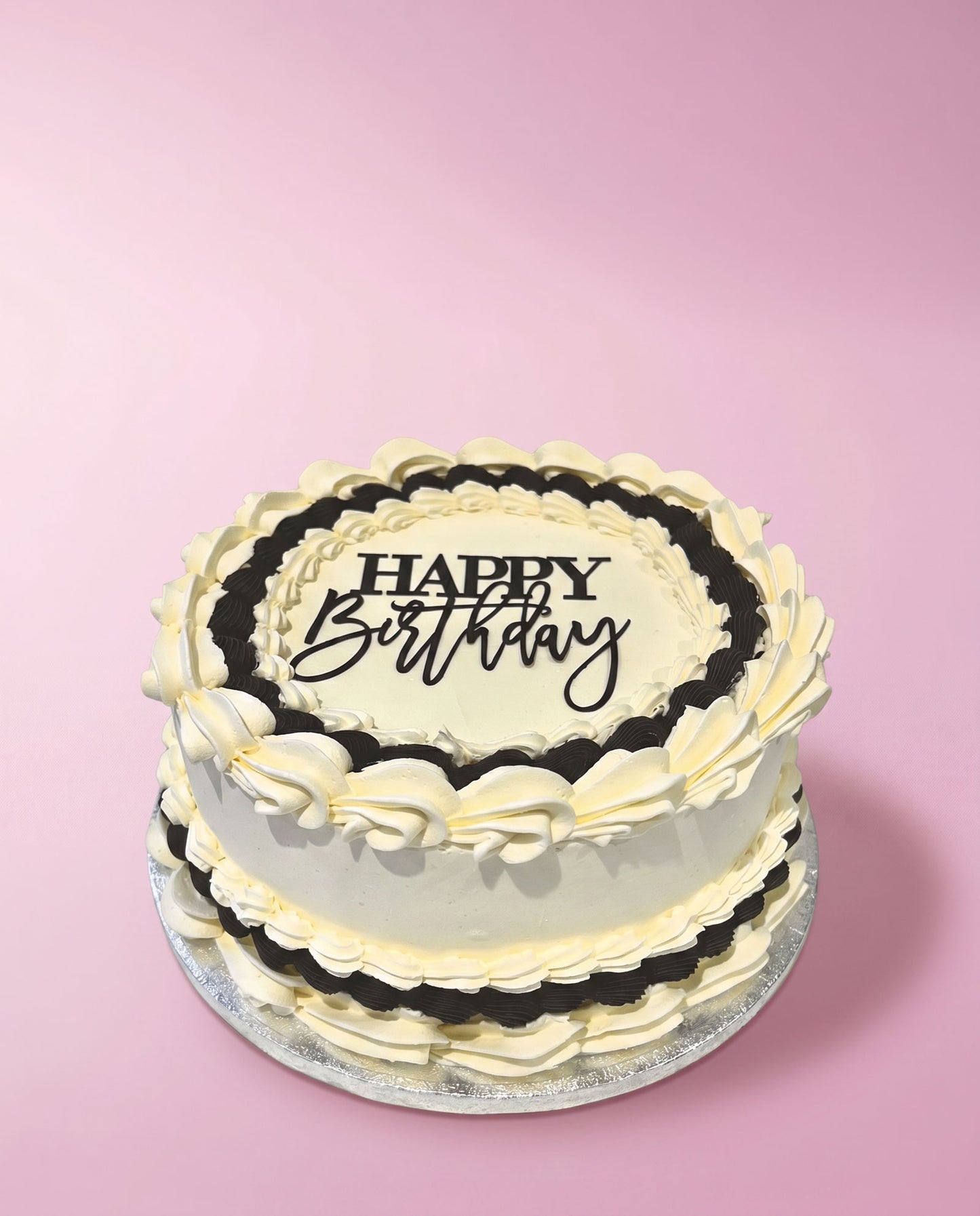 Black and white hand-piped buttercream celebration cake with a happy birthday topper, handmade by Daisy Mud Pie in Brentwood, Essex