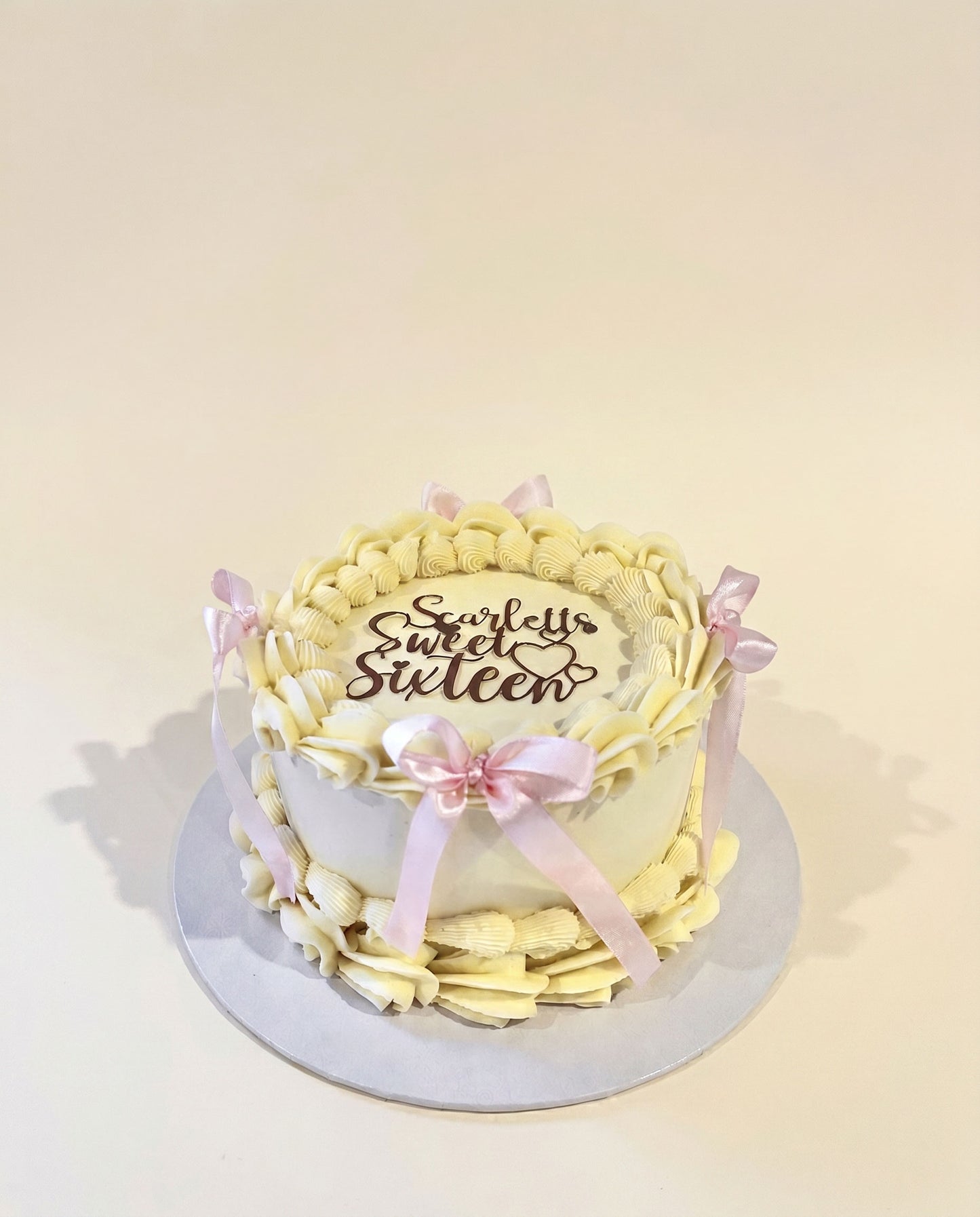 Buttercream celebration cake decorated with pink bows and a sweet sixteen topper, handmade by Daisy Mud Pie in Brentwood, Essex