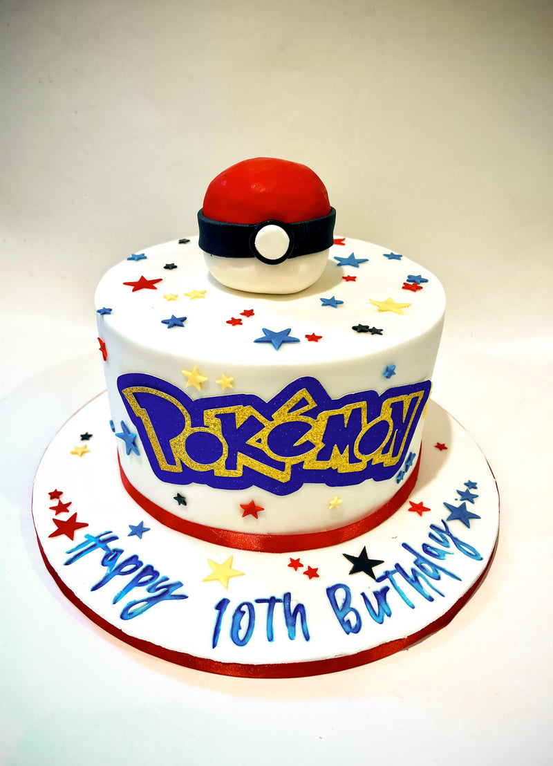 Pokémon themed fondant cake with red and white Pokéball topper, colourful star sprinkles and blue and yellow Pokémon lettering, handmade by Daisy Mud Pie in Brentwood, Essex