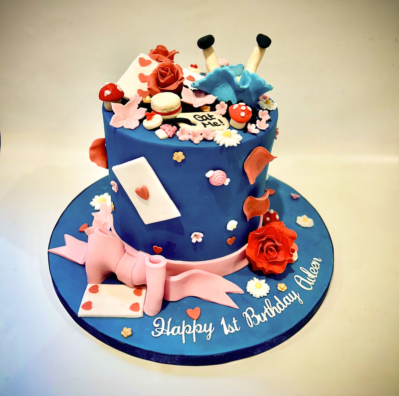 Alice in Wonderland themed fondant birthday cake with blue bird, red roses, mushroom details and pink ribbon, handmade by Daisy Mud Pie in Brentwood, Essex