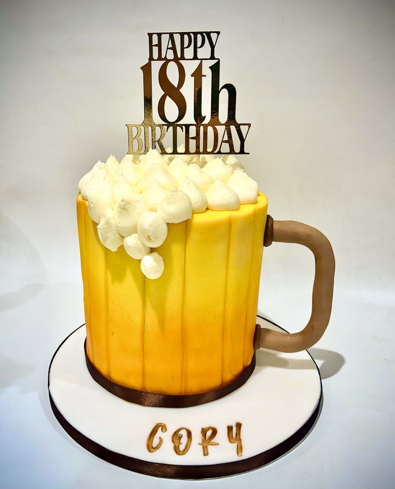 Novelty beer mug fondant birthday cake with yellow and orange stripes, whipped frosting overflow effect and personalised gold birthday topper, handmade by Daisy Mud Pie in Brentwood, Essex