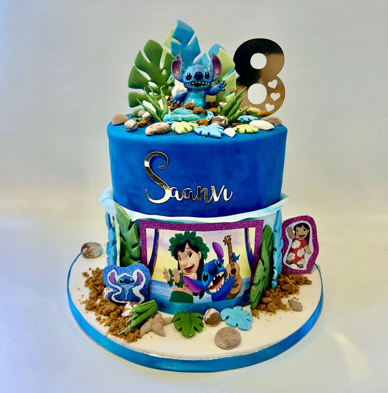 A custom Moana and Stitch themed birthday cake with a blue top tier, a decorated white bottom tier, and character decorations including a large number 8 topper, green leaves, and character portraits on a white background.